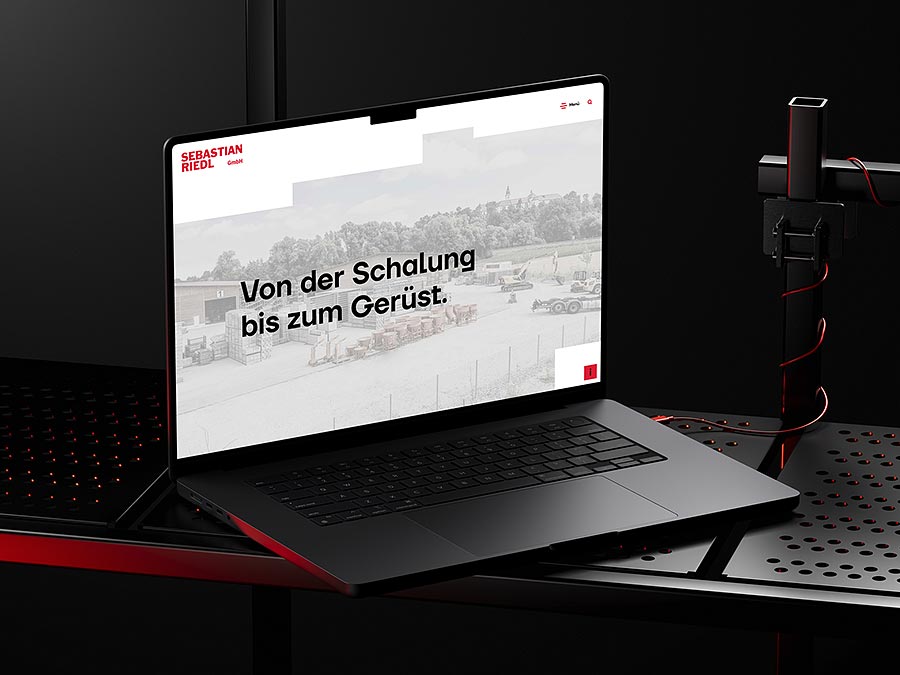 Laptop mit geöffneter Website der Sebastian Riedl GmbH. Die Startseite zeigt den Schriftzug 'Von der Schalung bis zum Gerüst' auf einer modernen, klar strukturierten Webdesign-Oberfläche für den Bau- und Gerüstbau-Sektor.